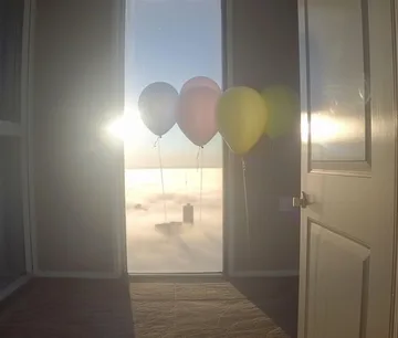 Balloons beside a sunlit doorway.