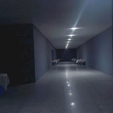 Empty blue-gray corridor with ceiling lights.