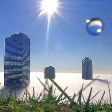 Bubbles floating above grass and distant towers.