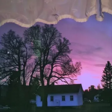 Curtains framing a house under a purple sky.