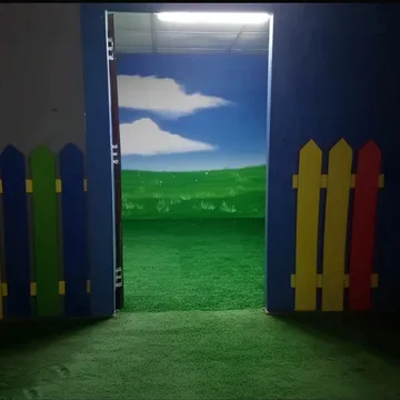 Small picket fence framing a door to green hills.