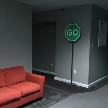 Red sofa beside a green sign in an empty room.