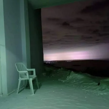 White chair beside an opening to a dark sky.