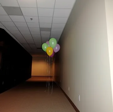 Balloons in a corridor leading into darkness.