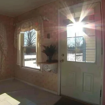 Sunlight through the windows of a wallpapered room.
