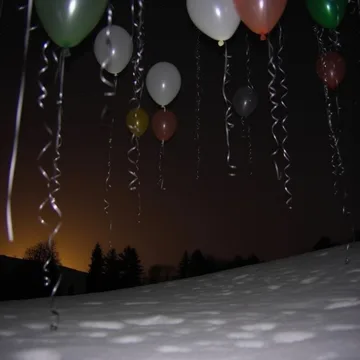 Balloons floating against a dark sunset.