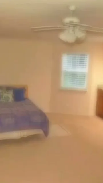 Softly blurred bedroom with a ceiling fan.