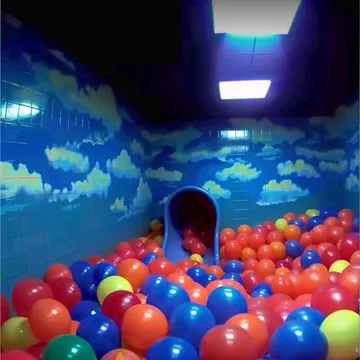 Ball pit in a room with cloud-painted walls.