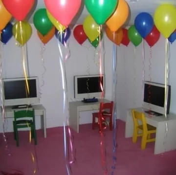 Balloons above old computers in a bright room.