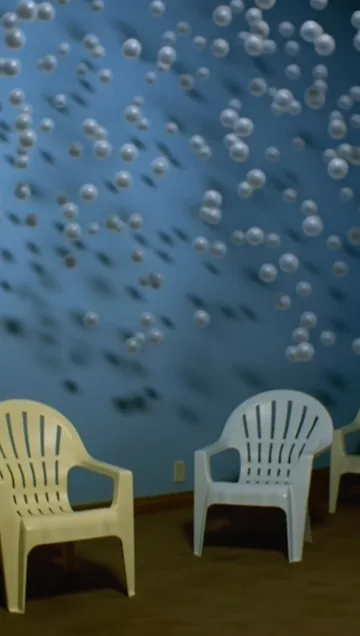 Two white chairs against a blue patterned wall.