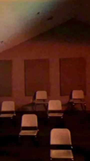 Rows of chairs inside a dark red room.