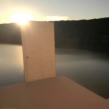 Open door beside a low sun and water.