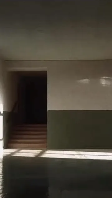 Shadowed room opening onto a staircase.