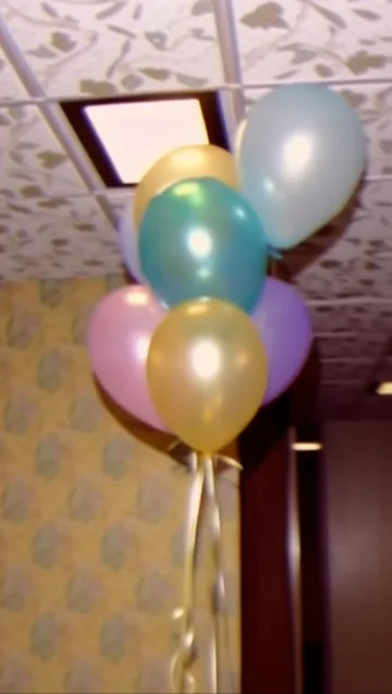 Pastel balloons against floral wallpaper.