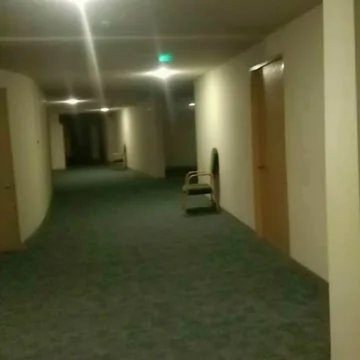 Long green hallway under ceiling lights.