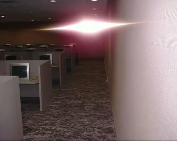 Rows of empty cubicles beneath a pink light.