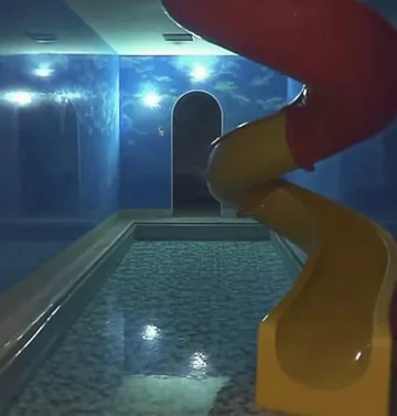 Yellow slide in a blue indoor pool.
