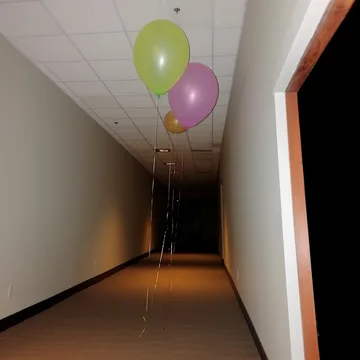 Balloons above a narrow corridor beside an open door.