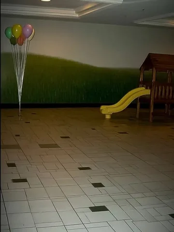 Small yellow slide on an empty tiled floor.