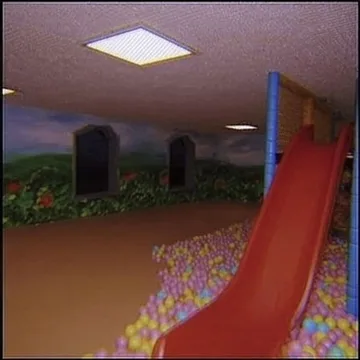 Red slide in a room filled with grass.