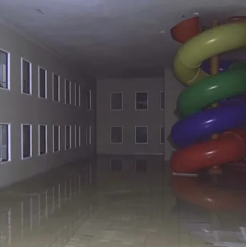 Rainbow spiral slide inside a dim apartment atrium.