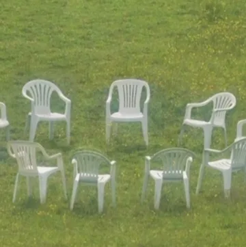 White chairs arranged on a green lawn.