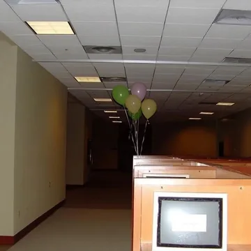 Computer and balloons in a dim empty room.