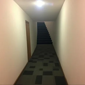 Narrow staircase beyond an empty corridor.
