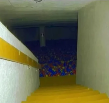 Yellow slide leading into a dark ball pit.