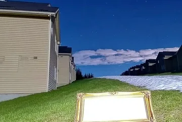 Outdoor chair between houses beneath a blue sky.