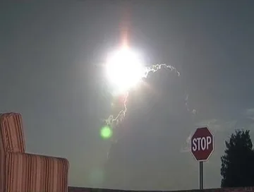 Stop sign beneath a bright light in the night sky.