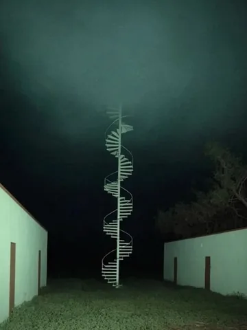 Spiral tower beneath dark storm clouds.