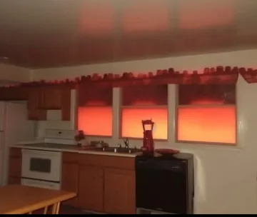 Kitchen with red sunset in its windows.
