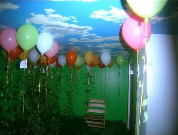 Balloons over a chair in a green room.
