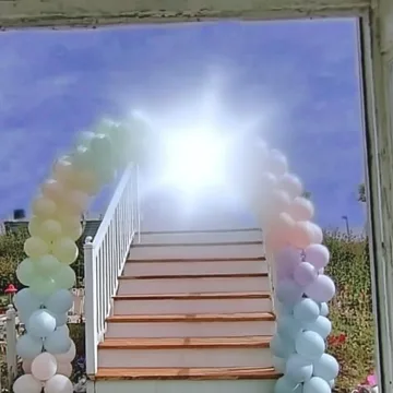 Balloon-lined stairs ascending into bright light.