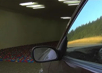 Car mirror beside a narrow empty corridor.