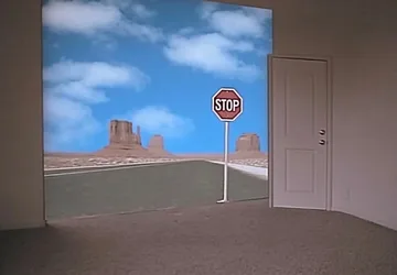 Open door facing a desert road and stop sign.