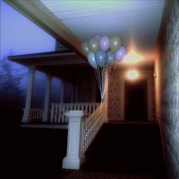 Balloons above a porch staircase at night.
