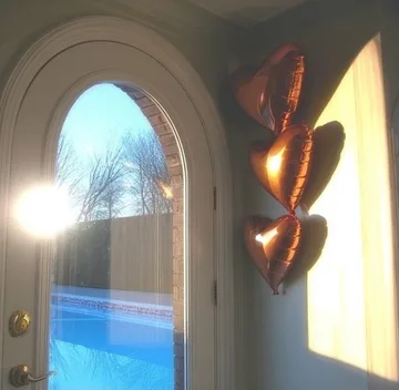 Gold balloons beside an arched sunlit door.