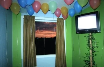 Old television and balloons in a green room.