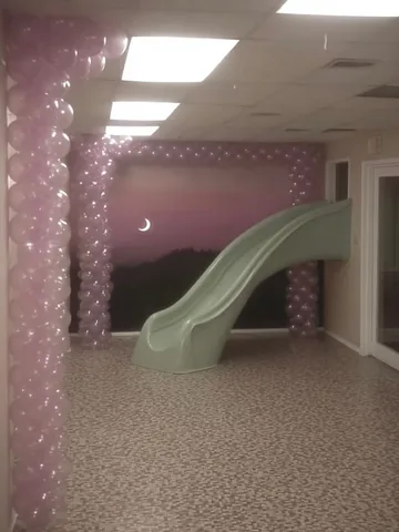 Pale slide beside a floral wall.