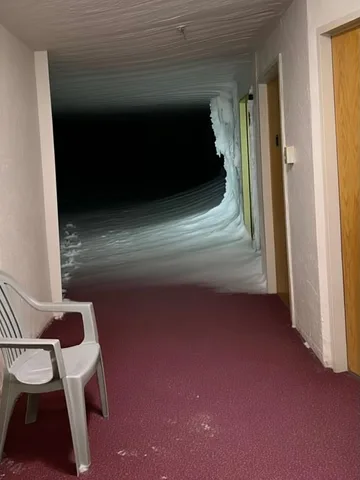 White chair beside a warped dark hallway.