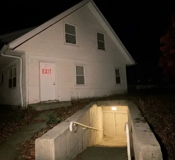 White house above an illuminated basement entrance at night.