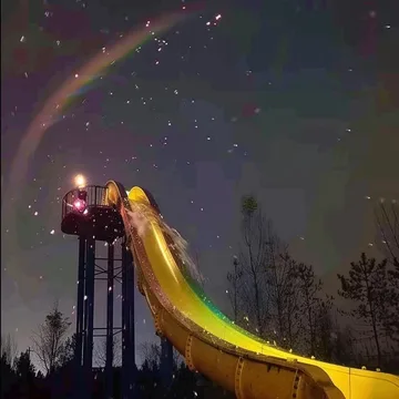 Water slide beneath a rainbow and night sky.