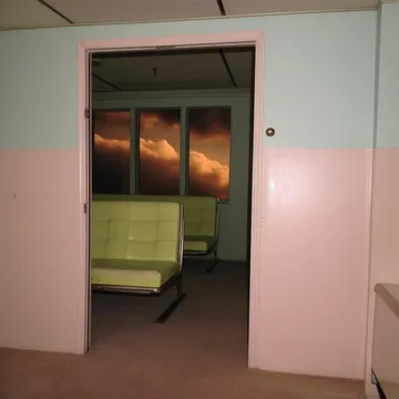Green waiting chairs beyond a pink doorway.