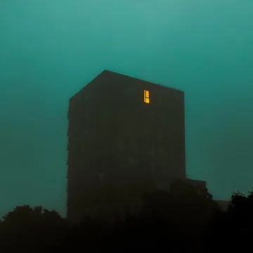 Dark tower with one lit window beneath a teal sky.