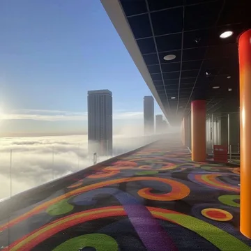 Patterned corridor above clouds and distant towers.