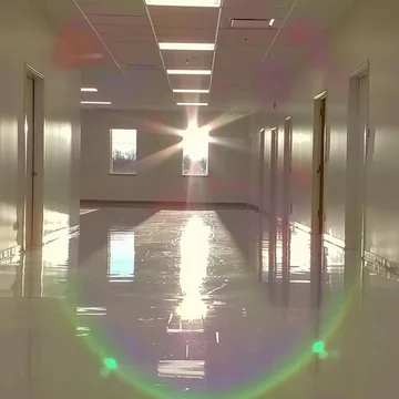 Rainbow flare down a reflective empty hallway.
