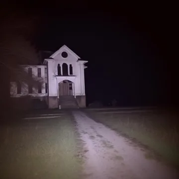 White house beside an empty road at night.