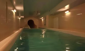 Indoor pool leading toward a dark round tunnel.